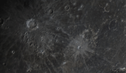 Copernicus is a prominent crater easily visible at a distance due to the bright ejecta radiating from the center of impact. The interior is marked by distinctive peaks and the rim has collapsed and eroded in sections. The the right, Kepler is surrounded by rays that extend 500km across the lunar surface.