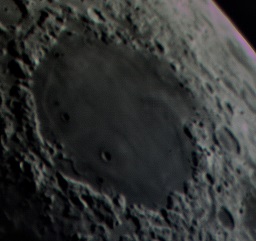 A prominent crater on a crescent moon.
