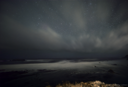 These are stars appearing above storm clouds hovering over the turbulent Pacific Ocean as it dashes against Gull Rock.