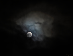 The moon shining brightly through thin cloud cover.