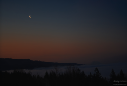 The crescent moon hovers above volcano Mt. Rainier just before the sun rises.