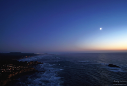 The crescent moon descends over the ocean off the coast of Oregon.