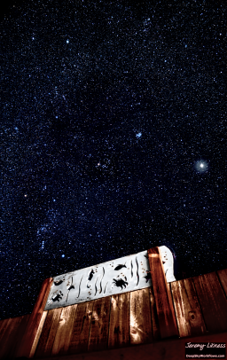 'Behind the fence.' A 45-second exposure taken last night for a timelapse. The bright object to the right is Jupiter. The bright cluster near the top middle is M45, the Pleiades, and the Orion constellation with brilliant Betelgeuse is in the lower left.